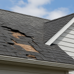 Close-up of a damaged roof with missing shingles and exposed wood