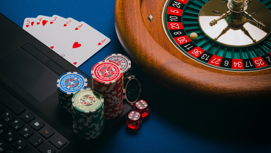 Close-up of poker chips, playing cards, and a roulette wheel on a blue table.